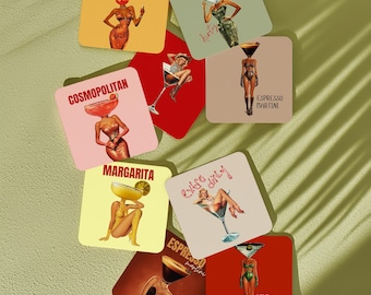 May include: A collection of square coasters featuring illustrations of figures with cocktail glasses for heads. The designs include text labels such as Aperol Spritz, Martini, Cosmopolitan, Espresso Martini, Margarita, Extra Dirty, and Dirty Martini.