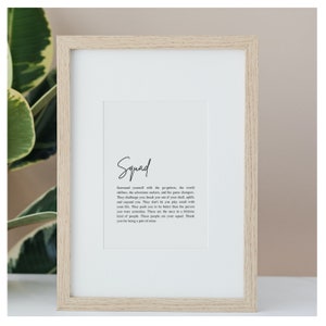 May include: A framed print with a white background and black text. The text reads "Squad" and then a definition of the word. The definition is about surrounding yourself with people who challenge you to be better.