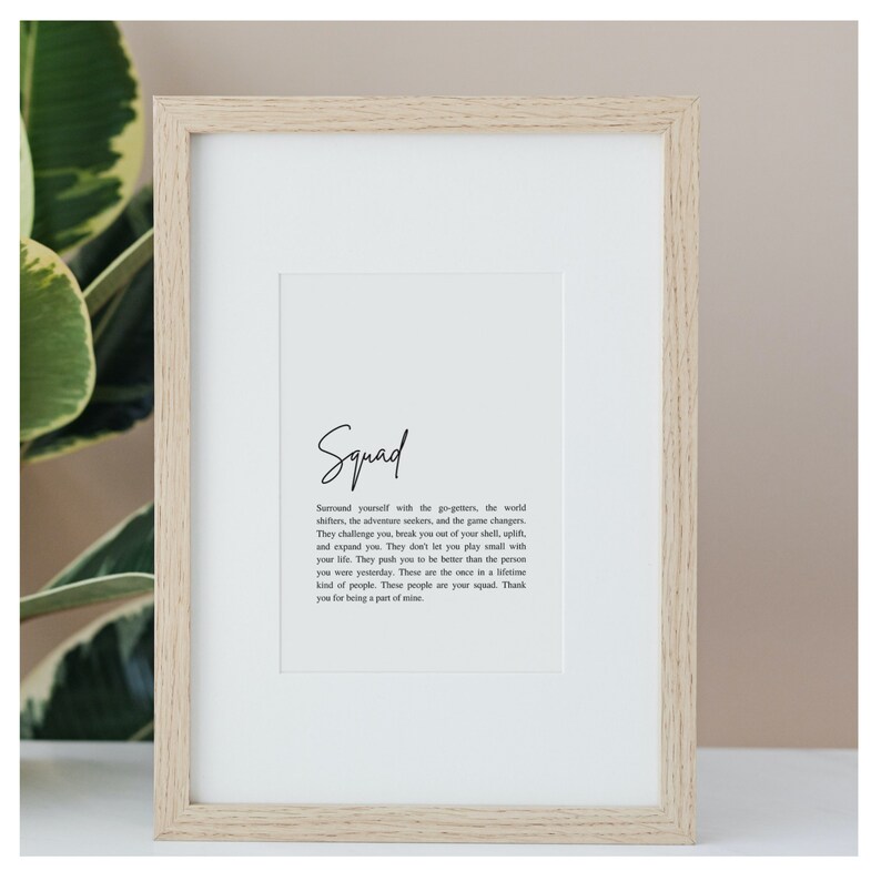 May include: A framed print with a white background and black text. The text reads "Squad" and then a definition of the word. The definition is about surrounding yourself with people who challenge you to be better.