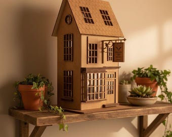 May include: A detailed wooden miniature house with a sign reading "Thimble & Spool Studio." The house features multiple windows and is displayed on a rustic wooden shelf, alongside potted plants. The house has a brown roof and walls.