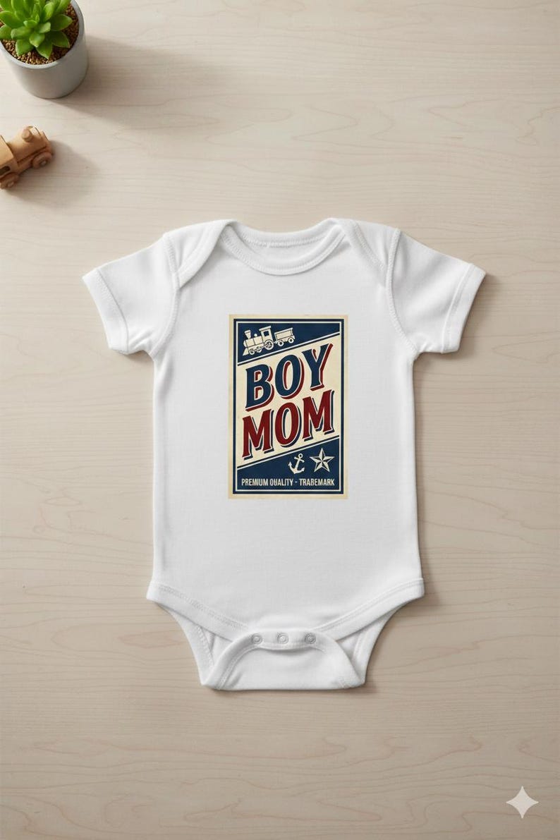 Puede incluir: Body de beb&eacute; blanco con un gr&aacute;fico azul marino y rojo que dice "BOY MOM". El dise&ntilde;o incluye un tren, un ancla y una estrella. Tambi&eacute;n se incluye el texto "PREMIUM QUALITY - TRADEMARK".