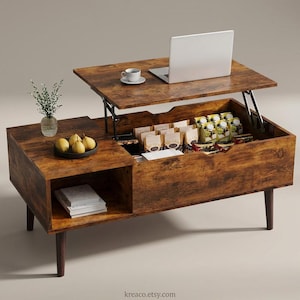 Puede incluir: Mesa de centro elevable de madera con acabado rústico. Tiene un ordenador portátil, una taza de café y un pequeño jarrón con vegetación. Dentro de la mesa hay aperitivos y bebidas. La mesa se apoya en cuatro patas de color marrón oscuro.