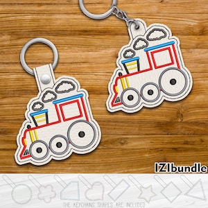 Peut inclure: Deux porte-clés de train brodés avec des détails rouges, bleus, jaunes et blancs. Les porte-clés sont sur un fond en bois. Le texte "IZLibundle" est visible dans le coin inférieur droit de l'image. Le texte "THE KEYCHAINS SHAPES ARE INCLUDED" est visible dans le centre inférieur de l'image.