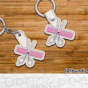 May include: Two white leather keychains with a pink comb and silver scissors design. The keychains are on a wooden background. The text "IZLibundle" is at the bottom of the image. The keychains are available in various shapes, including a circle, flower, rectangle, heart, star, diamond, and triangle.