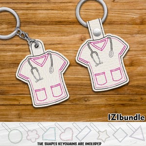 May include: White scrub top keychain with pink stitching and a stethoscope design. The keychain is attached to a silver key ring. The image also shows various shapes of keychains, including a circle, star, heart, and rectangle.