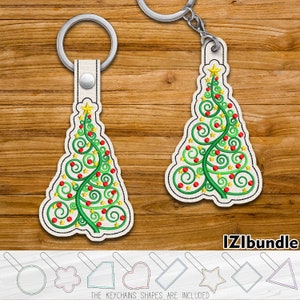 May include: Two Christmas tree-shaped keychains with green, red, and gold embroidery. The keychains are on a wooden background. The keychains shapes are included.