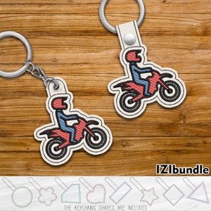 May include: Two motorcycle-themed keychains with a rider in red and blue, attached to silver keyrings. The keychains are embroidered on a cream-colored background. The image also includes various keychain shape templates and the text "IZIbundle".