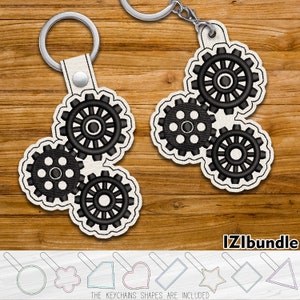 May include: A set of three interlocking gears in black and white, with a white background. The gears are attached to a leather keychain with a silver ring. The keychain is on a wooden surface. The text "IZIbUNDLE" is visible in the bottom right corner of the image. The text "THE KEYCHAINS SHAPES ARE INCLUDED" is visible in the bottom center of the image.