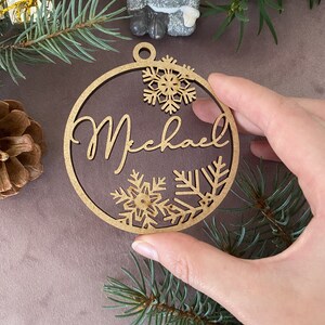 Pu&ograve; includere: Un ornamento di Natale in legno con il nome "Michael" scritto in corsivo. L'ornamento &egrave; decorato con fiocchi di neve.