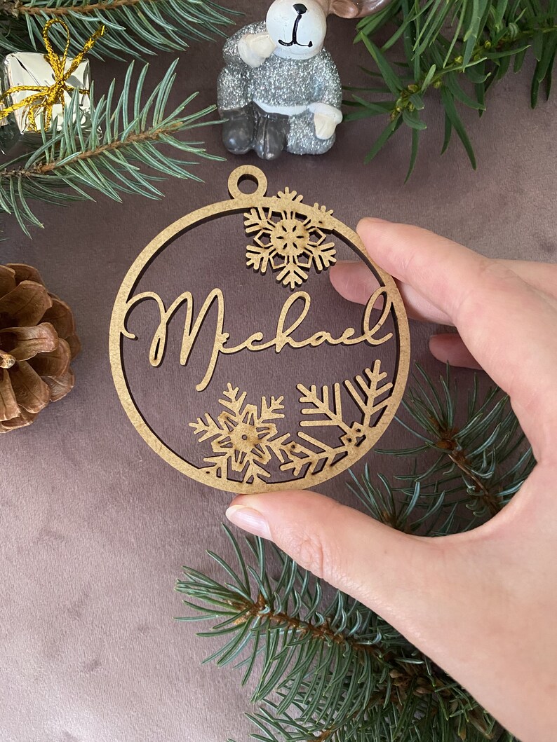 Pu&ograve; includere: Un ornamento di Natale in legno con il nome "Michael" scritto in corsivo. L'ornamento &egrave; decorato con fiocchi di neve.