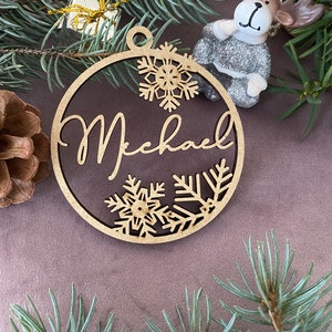 Pu&ograve; includere: Un ornamento natalizio in legno con il nome "Michael" ritagliato al centro. L'ornamento &egrave; decorato con fiocchi di neve e ha una finitura marrone rustica.