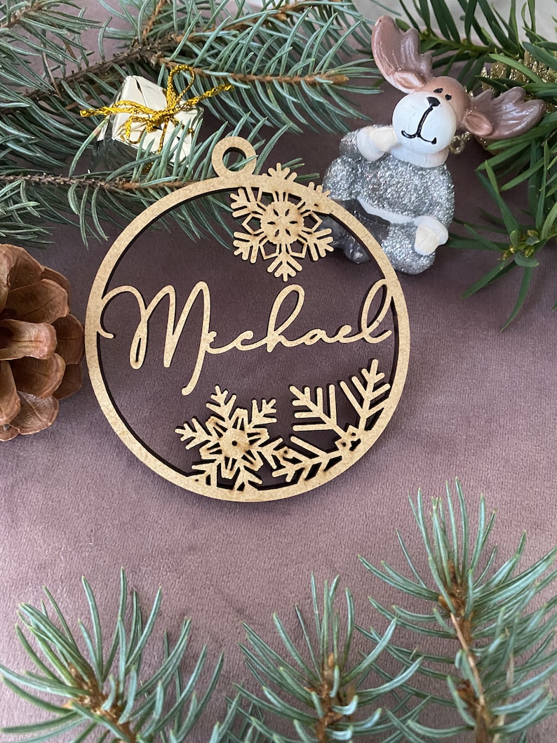 Pu&ograve; includere: Un ornamento natalizio in legno con il nome "Michael" ritagliato al centro. L'ornamento &egrave; decorato con fiocchi di neve e ha una finitura marrone rustica.