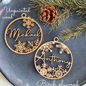 Pu&ograve; includere: Due decorazioni natalizie in legno non verniciate con motivi a fiocco di neve. Le decorazioni sono personalizzate con i nomi "Michael" e "Anthony". Le decorazioni sono in compensato di betulla.