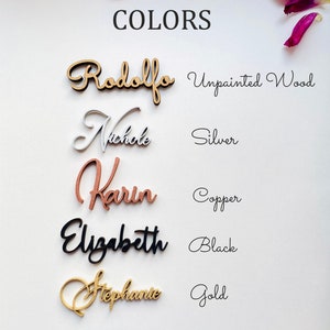 Pu&ograve; includere: Cinque targhette in legno con nomi in diversi colori, tra cui legno non verniciato, argento, rame, nero e oro. La parola "COLORS" &egrave; scritta nella parte superiore dell'immagine.