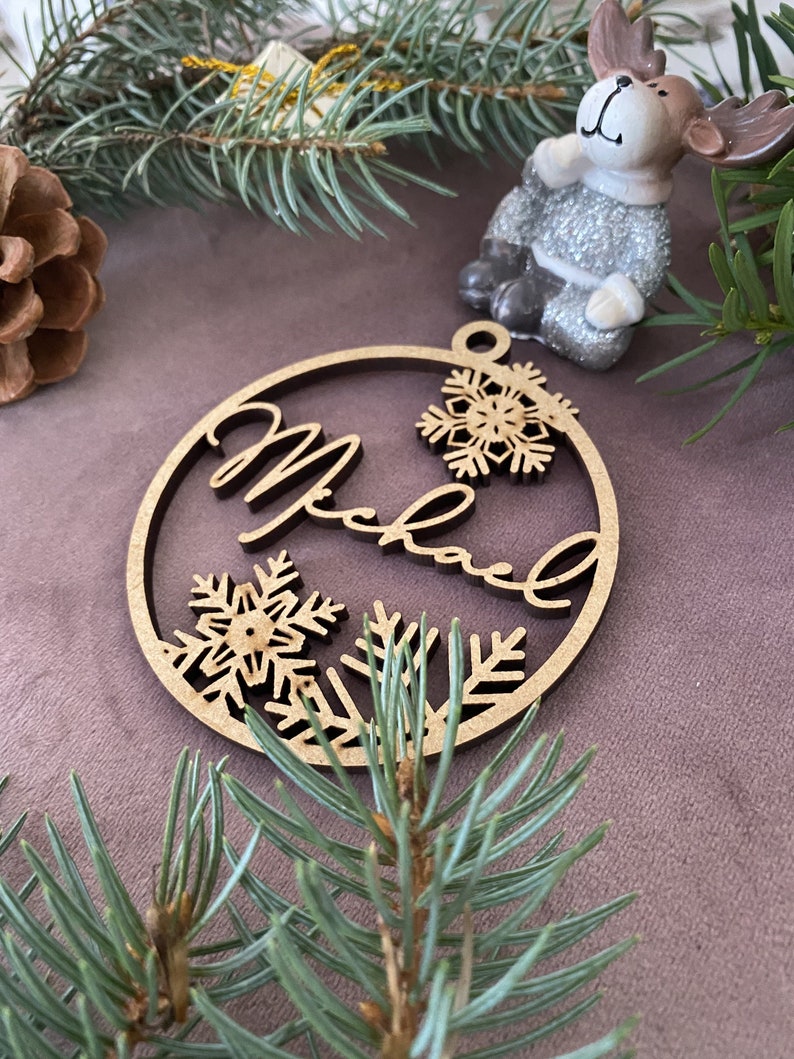 Pu&ograve; includere: Un ornamento natalizio in legno con il nome "Michael" inciso. L'ornamento &egrave; decorato con fiocchi di neve e ha un foro nella parte superiore per appenderlo.