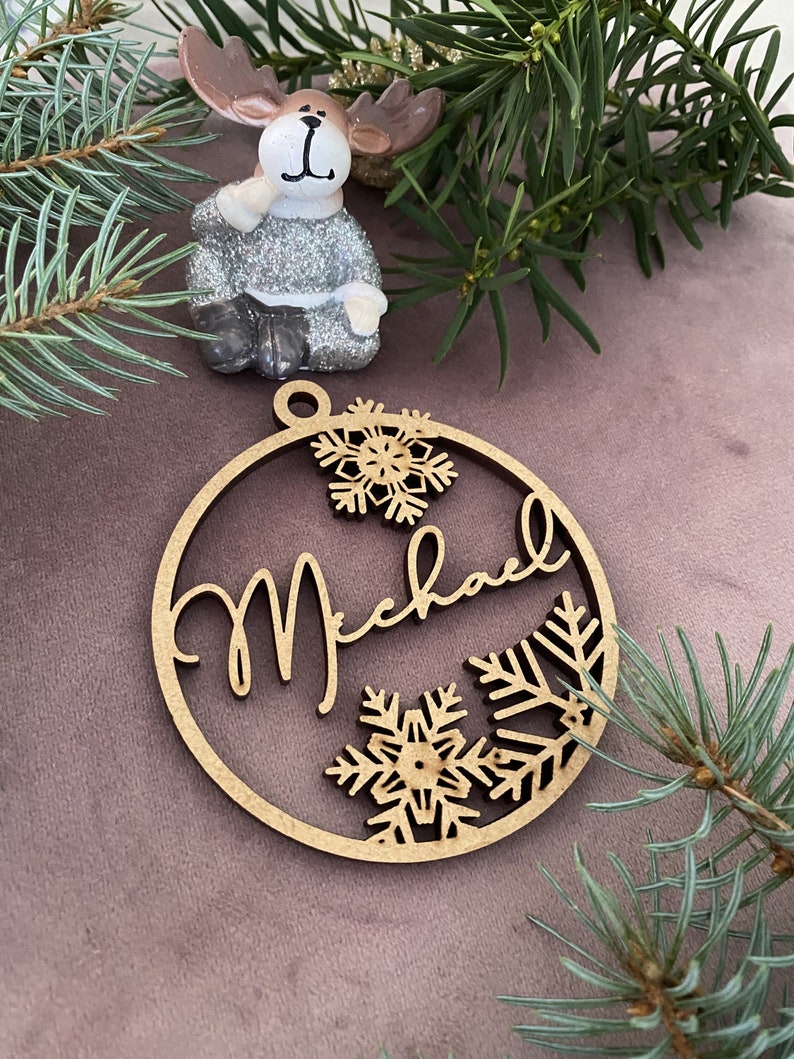 Pu&ograve; includere: Un ornamento natalizio in legno con il nome "Michael" scritto in corsivo. L'ornamento &egrave; decorato con fiocchi di neve e ha un foro nella parte superiore per appenderlo.