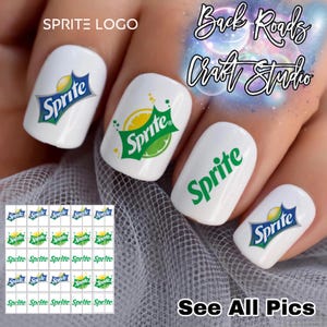 May include: White nail art featuring the Sprite logo in various designs. Some nails display the logo with a lemon and lime graphic, while others show the logo in green and blue. The image also includes a sheet of Sprite nail decals.
