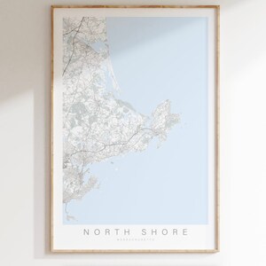 May include: A framed map of the North Shore of Massachusetts, with a light blue background and gray lines representing roads and waterways. The text "NORTH SHORE MASSACHUSETTS" is printed at the bottom of the map.