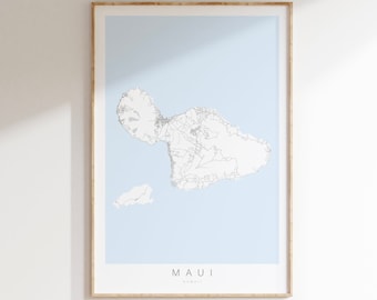 May include: A framed map of Maui, Hawaii, with a light blue background and white lines showing the island's roads and coastline. The word "MAUI" is printed in gray at the bottom of the map.
