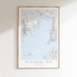 May include: A framed map print of Buzzards Bay, Massachusetts, featuring a detailed topographical layout in shades of gray and white against a light blue background. The print includes the bay's name and coordinates.