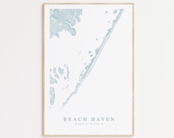 May include: A framed print of a map of Beach Haven, New Jersey, in a light blue color. The coordinates 39.5593° N, 74.2432° W are printed below the name of the town.