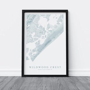Puede incluir: Una impresi&oacute;n enmarcada en negro con un mapa de acuarela de Wildwood Crest, Nueva Jersey. El mapa est&aacute; en tonos de azul y blanco y muestra la costa y las v&iacute;as fluviales circundantes. El texto "Wildwood Crest" y las coordenadas "39.0117&deg; N, 74.8387&deg; W" est&aacute;n impresas debajo del mapa.