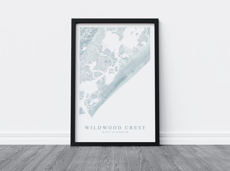 Puede incluir: Una impresi&oacute;n enmarcada en negro con un mapa de acuarela de Wildwood Crest, Nueva Jersey. El mapa est&aacute; en tonos de azul y blanco y muestra la costa y las v&iacute;as fluviales circundantes. El texto "Wildwood Crest" y las coordenadas "39.0117&deg; N, 74.8387&deg; W" est&aacute;n impresas debajo del mapa.