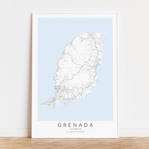 May include: A minimalist black and white map print of Grenada, a Caribbean island, with a light blue background. The map shows the island's roads and rivers. The text "GRENADA" and "CARIBBEAN" are printed below the map, along with the coordinates "12.1155&deg; N, 61.4790&deg; W".