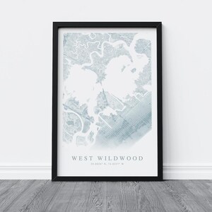 May include: A framed map print of West Wildwood, featuring a detailed, light blue and white topographical design. The print is encased in a black frame and includes the text "WEST WILDWOOD" and coordinates.