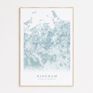 May include: A framed art print featuring a map of Hingham, Massachusetts, in shades of blue and white. The abstract design resembles a topographical view. The town's name and coordinates are printed at the bottom.