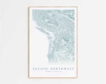 May include: A framed print of a blue and white map of the Pacific Northwest region. The map is titled "Pacific Northwest" with the coordinates "48.7480° N, 122.2237° W" printed below the title.