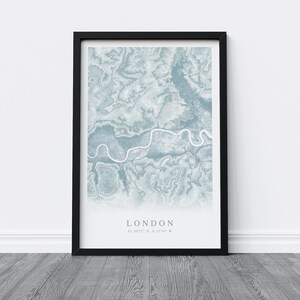 May include: A framed print of a map of London in blue and white. The map shows the Thames River winding through the city. The text "LONDON 51.5074&deg; N, 0.1278&deg; W" is printed below the map.