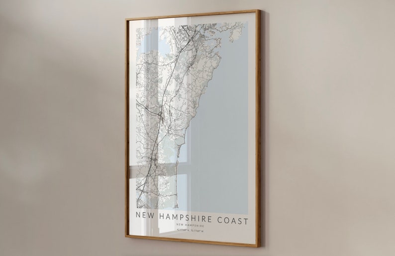 K&ouml;nnte beinhalten: Ein gerahmter Kartenabdruck der K&uuml;ste von New Hampshire mit hellblauem Hintergrund und schwarzen Linien, die Stra&szlig;en und Wasserwege darstellen. Der Text "NEW HAMPSHIRE COAST" ist unten auf der Karte gedruckt.