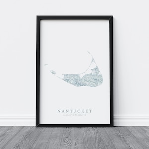 K&ouml;nnte beinhalten: Ein schwarzer gerahmter Druck mit wei&szlig;em Hintergrund, der eine hellblaue Aquarell-Illustration der Insel Nantucket zeigt. Der Text "NANTUCKET 41.2819&deg; N, 70.1008&deg; W" ist unter der Illustration gedruckt.