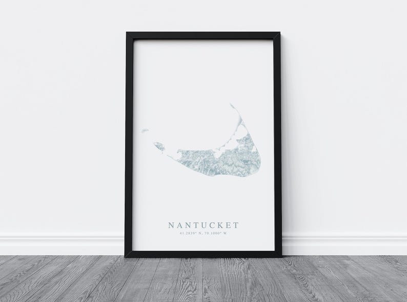 K&ouml;nnte beinhalten: Ein schwarzer gerahmter Druck mit wei&szlig;em Hintergrund, der eine hellblaue Aquarell-Illustration der Insel Nantucket zeigt. Der Text "NANTUCKET 41.2819&deg; N, 70.1008&deg; W" ist unter der Illustration gedruckt.