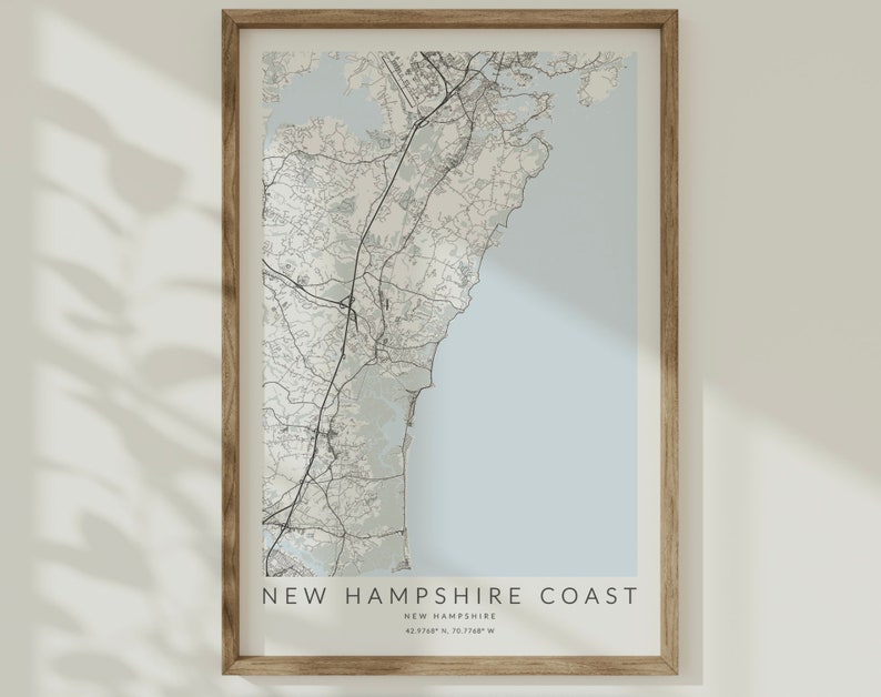 K&ouml;nnte beinhalten: Eine gerahmte Karte der K&uuml;ste von New Hampshire mit hellblauem Hintergrund und schwarzen Linien, die die Stra&szlig;en und Wasserwege zeigen. Der Text "NEW HAMPSHIRE COAST" ist unten auf der Karte gedruckt, zusammen mit den Koordinaten "43.3748&deg; N, 70.7348&deg; W".