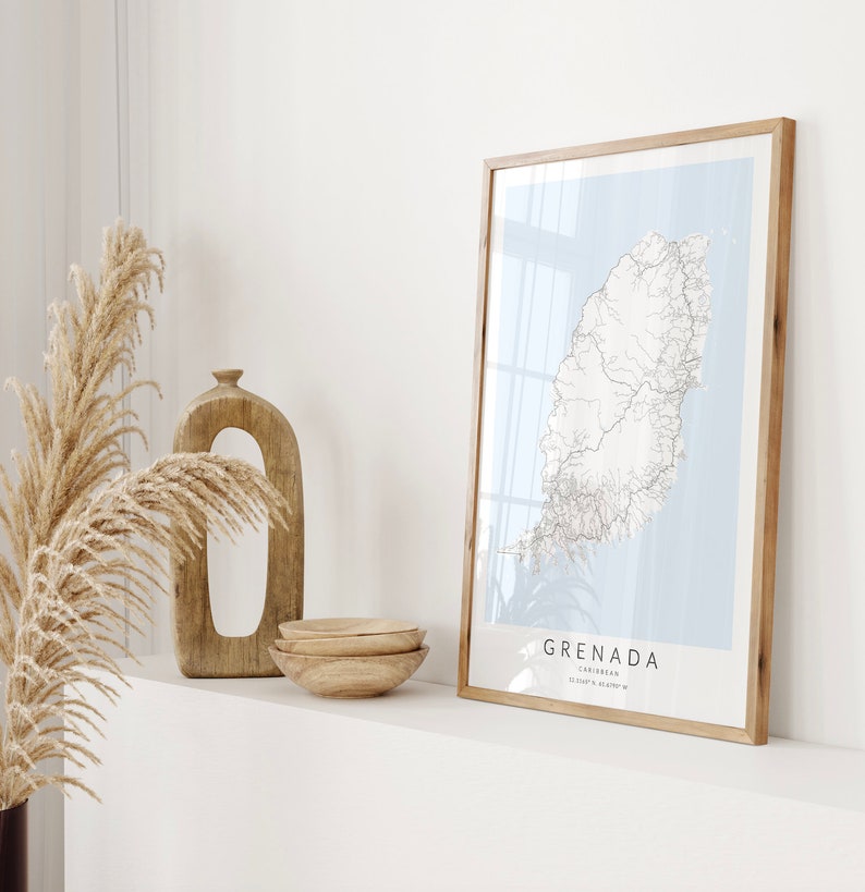 May include: A framed map of Grenada, a Caribbean island, with a light blue background and black lines representing roads and rivers. The frame is made of natural wood and the map is titled "Grenada, Caribbean, 12.11&deg;N 61.68&deg;W".