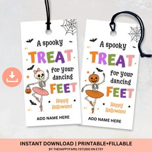 May include: Two white Halloween-themed gift tags with black string. Each tag features a skeleton ballerina and the text "A spooky TREAT for your dancing FEET." One skeleton has a bow, the other a pumpkin head. Bats and stars decorate the tags.