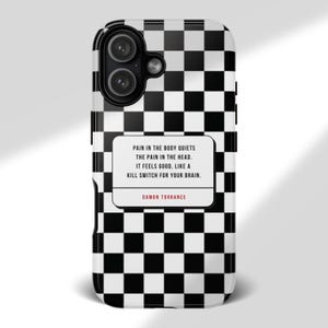May include: A black and white checkered phone case with a quote by Damon Torrance. The quote reads: "PAIN IN THE BODY QUIETS THE PAIN IN THE HEAD. IT FEELS GOOD, LIKE A KILL SWITCH FOR YOUR BRAIN."