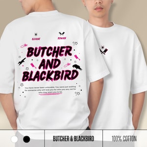 May include: A white t-shirt featuring a graphic design with the text "BUTCHER AND BLACKBIRD" in large black and pink letters. The design includes small icons of spiders, cleavers, chainsaws, stars, and crows, along with the names "SLOANE" and "ROWAN".