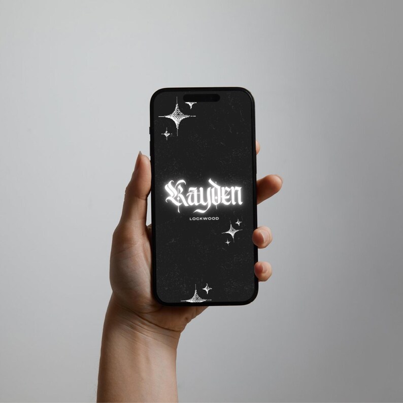 May include: A black smartphone displaying a dark screen with white star icons and the text Kayden Lockwood in a gothic font. The display features a subtle grainy texture throughout the background, creating a high-contrast visual effect on the device.