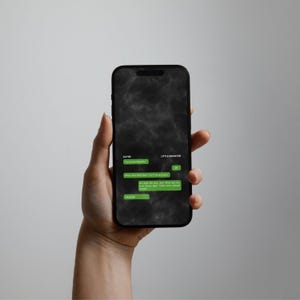 May include: A black smartphone displaying a dark, smoky background with a green text message conversation interface. The screen shows chat bubbles between Kayde and Little Monster, featuring text that includes phrases like You looked beautiful.