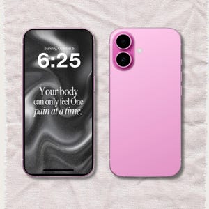 以下が含まれることがあります： ピンク色のスマートフォン。黒い画面には6時25分と「Your body can only feel One pain at a time.」の文字が表示されています。スマートフォンの背面には2つのカメラレンズがあります。画像は、質感のあるオフホワイトの背景に配置されています。