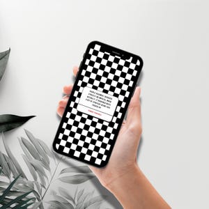 以下が含まれることがあります： 黒いスマートフォンは、画面に白と黒の市松模様を表示しています。白いボックスに引用文も表示されています。スマートフォンは、ニュートラルな背景に対して、手で持たれています。引用文は「People assumed I behaved...」と書かれています。