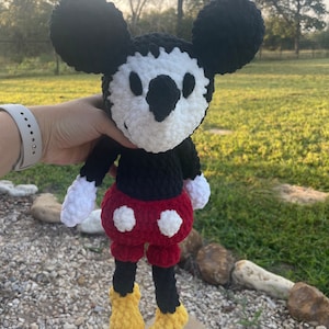 May include: A crocheted black and white Mickey Mouse plush toy with red shorts and yellow shoes.