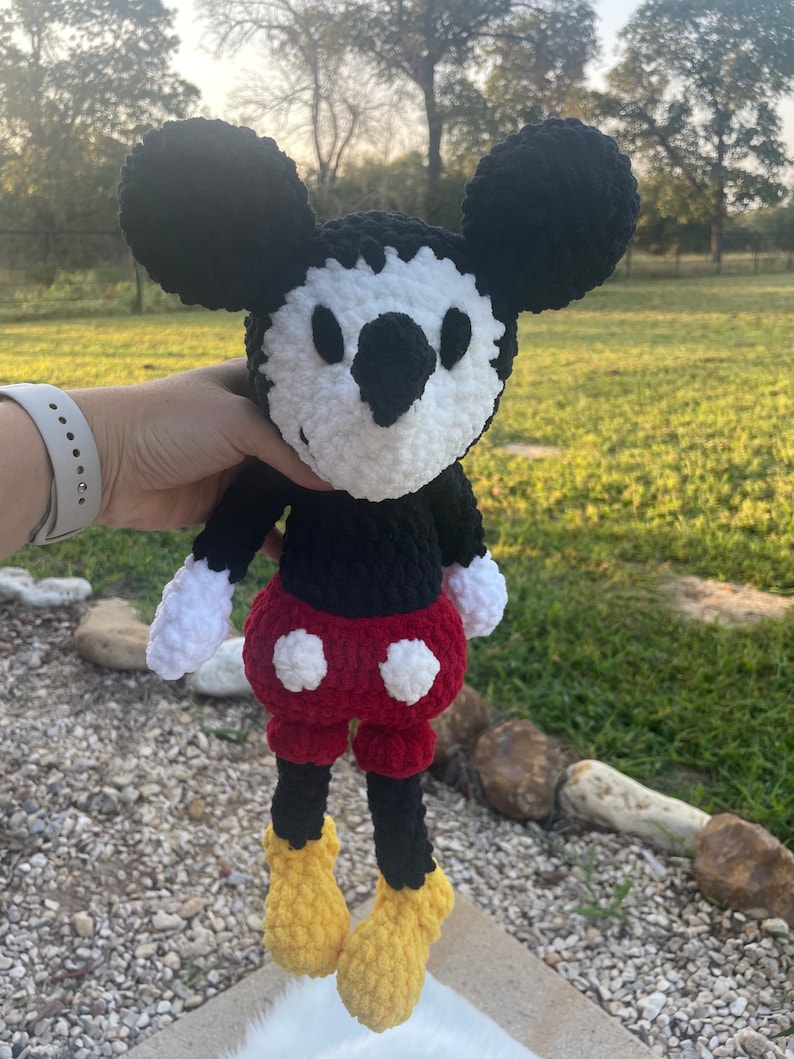 May include: A crocheted black and white Mickey Mouse plush toy with red shorts and yellow shoes.