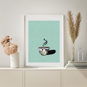 Könnte beinhalten: Eine weiße Keramiktasse mit einem schwarzen und gelben Design, gefüllt mit einer braunen Flüssigkeit und aufsteigendem Dampf, auf einem hellblauen Hintergrund.
