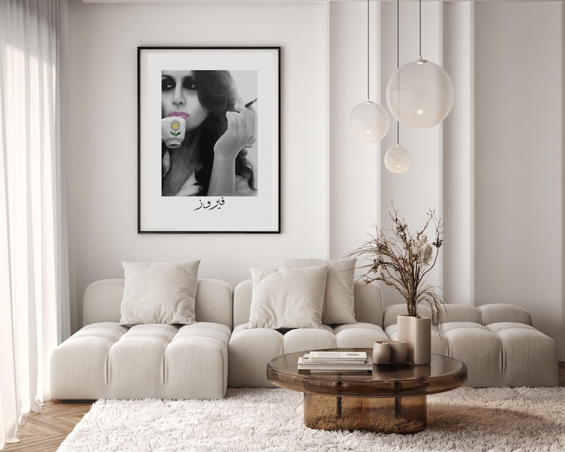 May include: A black and white photo of a woman holding a cup and smoking a cigarette. The photo is framed in a black frame and hanging on a white wall. The text "فروغ فرخزاد" is written below the photo.