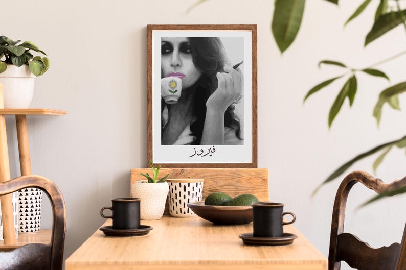 May include: Black and white photo of a woman holding a cup with a flower design. The photo is framed in a brown frame and has the text "قَوِيَّة" written below the image.