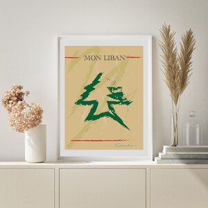 May include: A beige poster with a green stylised cedar tree and the text "MON LIBAN" in black. The poster has a red line at the top and bottom and a signature at the bottom right.